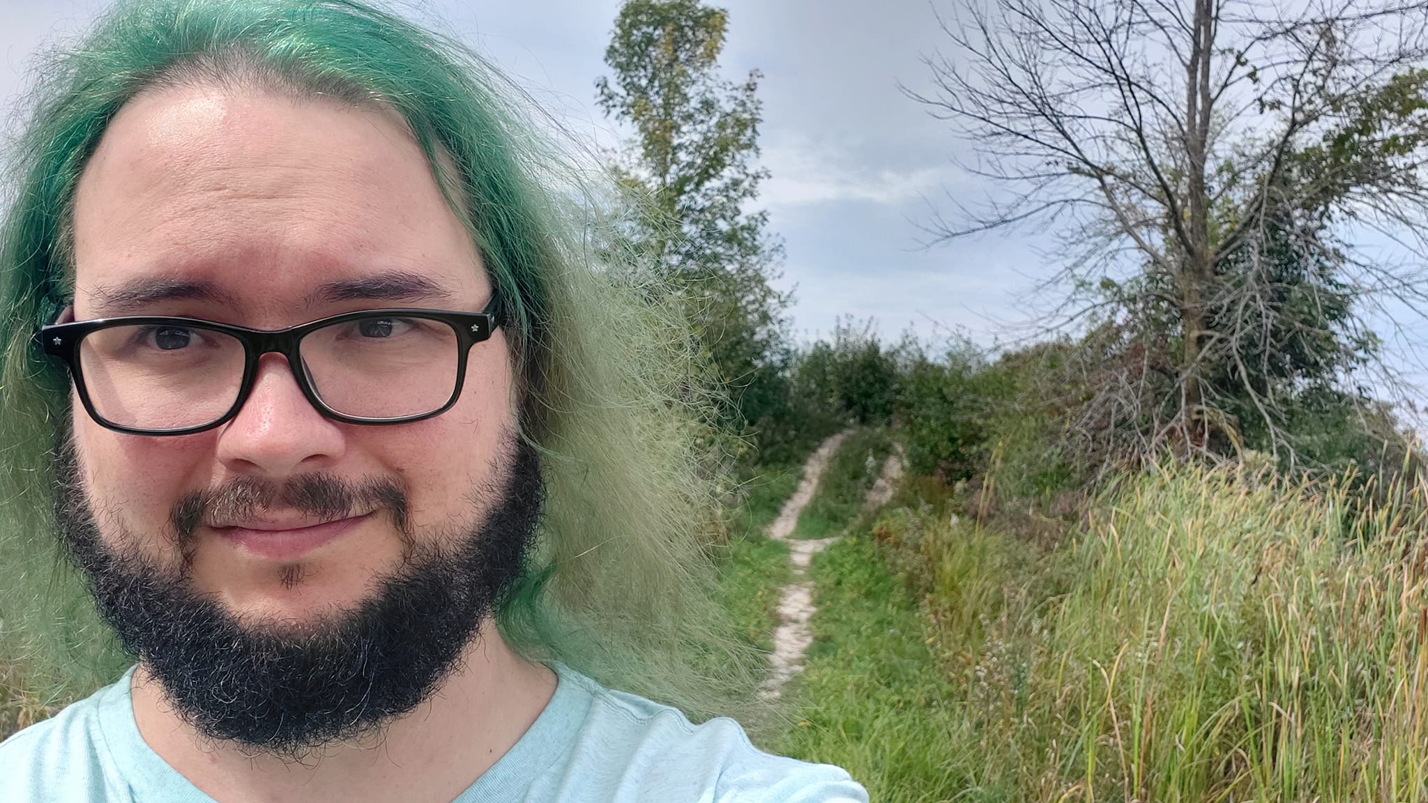 A man with green hair stands in front of a small hill, Photo 2